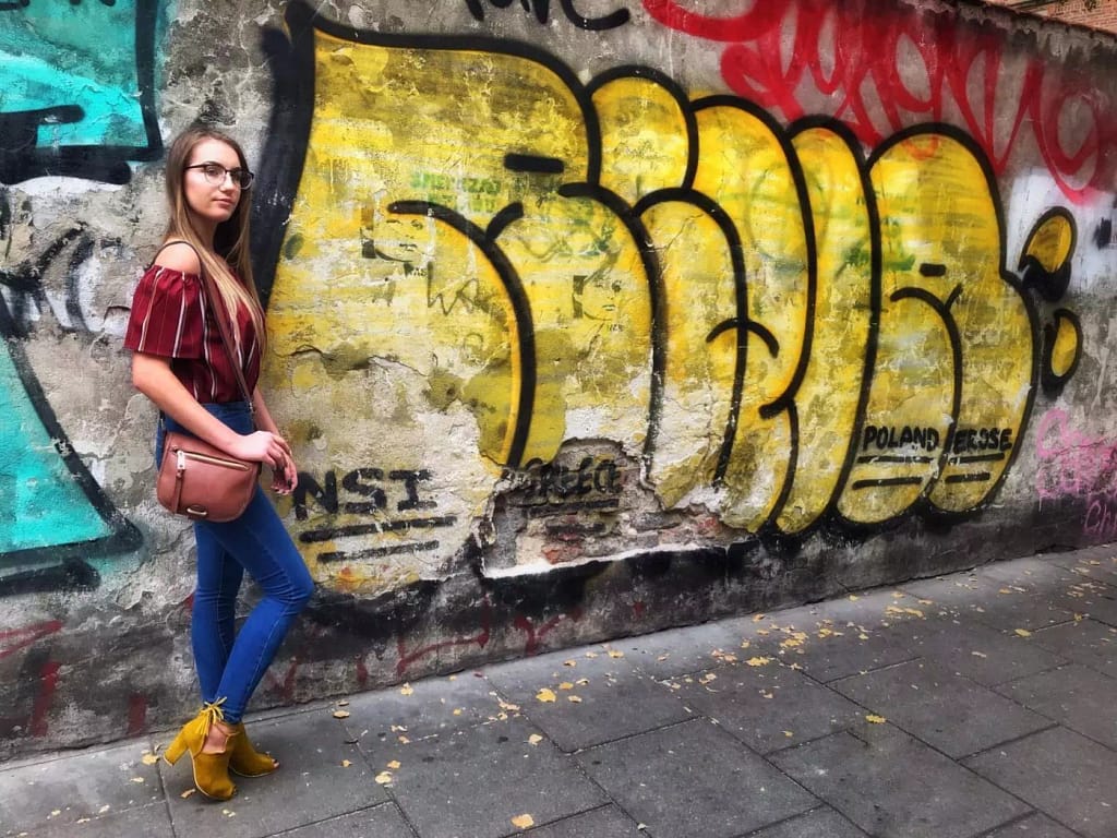 woman[posing in front of graffiti art on the Poland photography tour