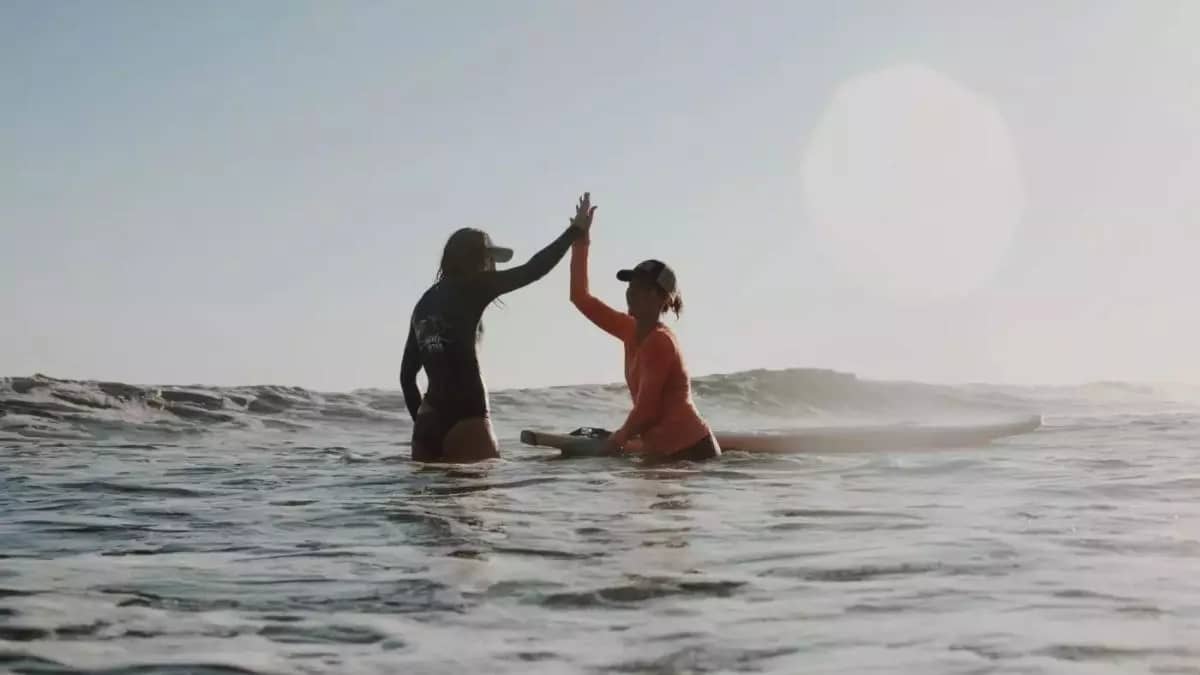 Image of women high five while surfing in el salvador