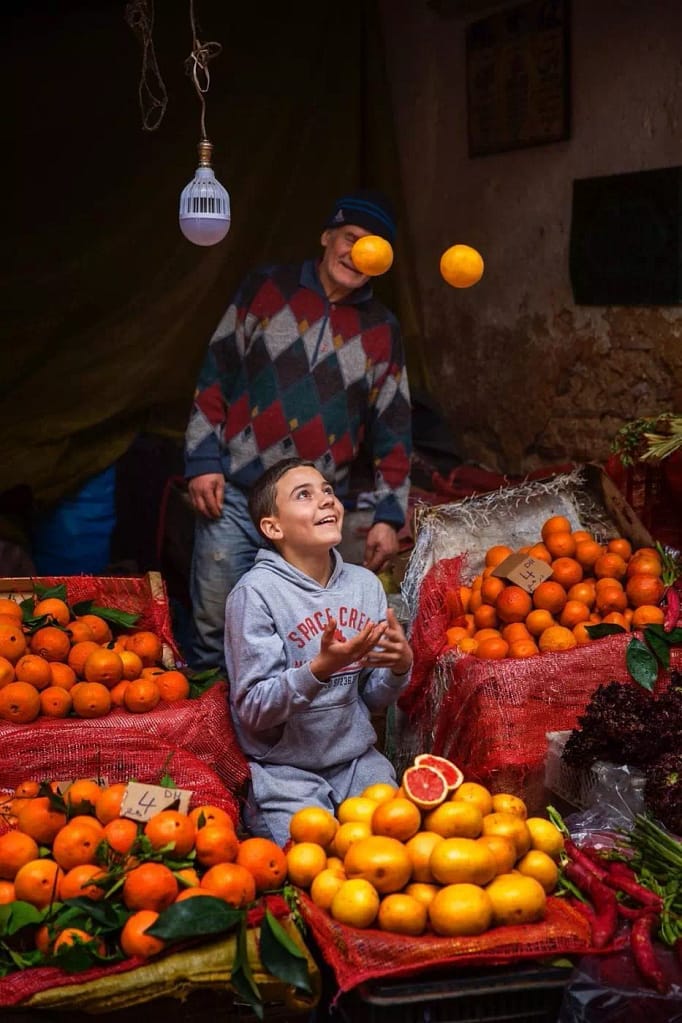 Boy juggling with fruit in Moroccan market